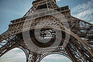 Bottom view of Eiffel Tower made in iron and Art Nouveau style, with sunny blue sky in Paris.